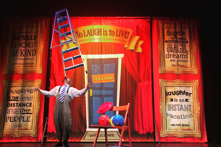man balancing a ladder on his head on a stage