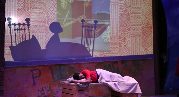 Boy laying on a bed with shadow on the wall