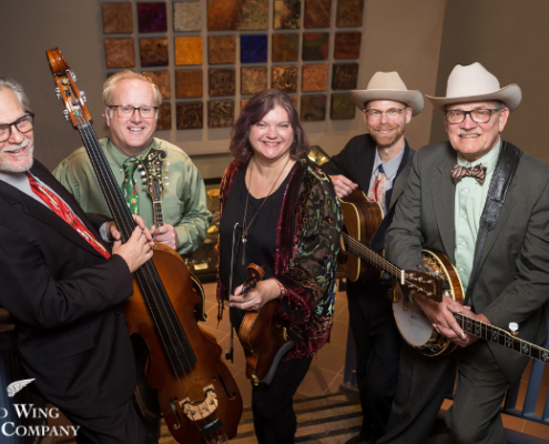 Monroe Crossing - May 15 bluegrass band holding instruments on standing on stairs